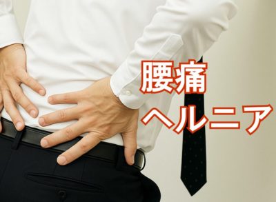 腰の痛みを感じているスーツ姿の男性の後ろ姿